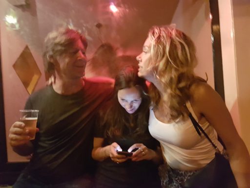 Een man en een vrouw lachen terwijl een meisje op haar telefoon kijkt.